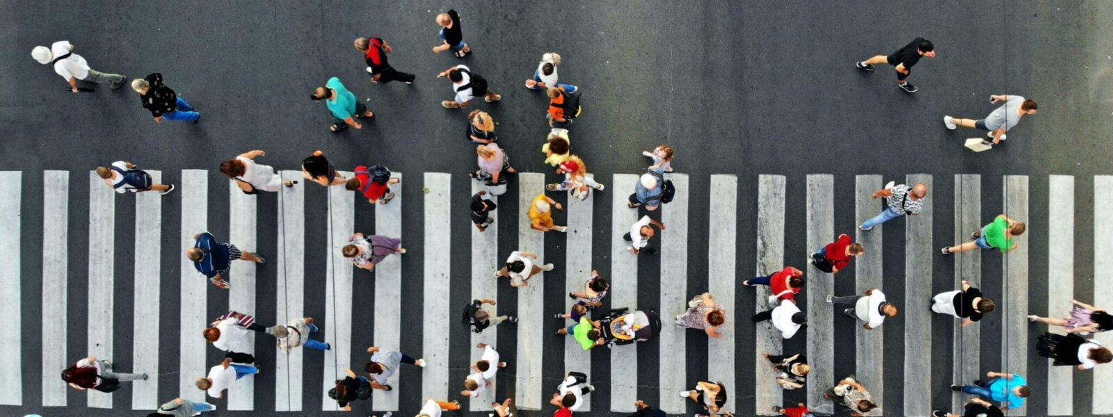 Aerial. People crowd motion through the pedestrian crosswalk. Top view from drone.