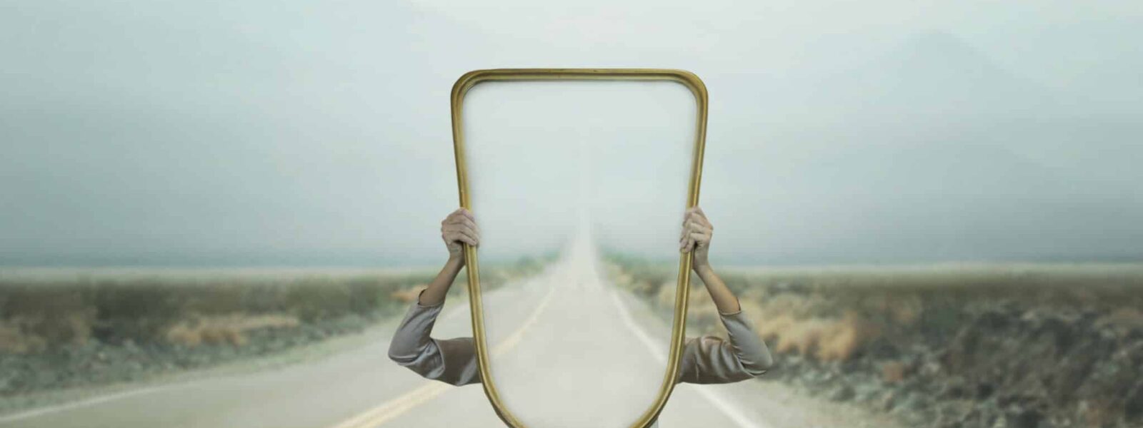 the woman hides holding a mirror in front of her face; introspection path concept