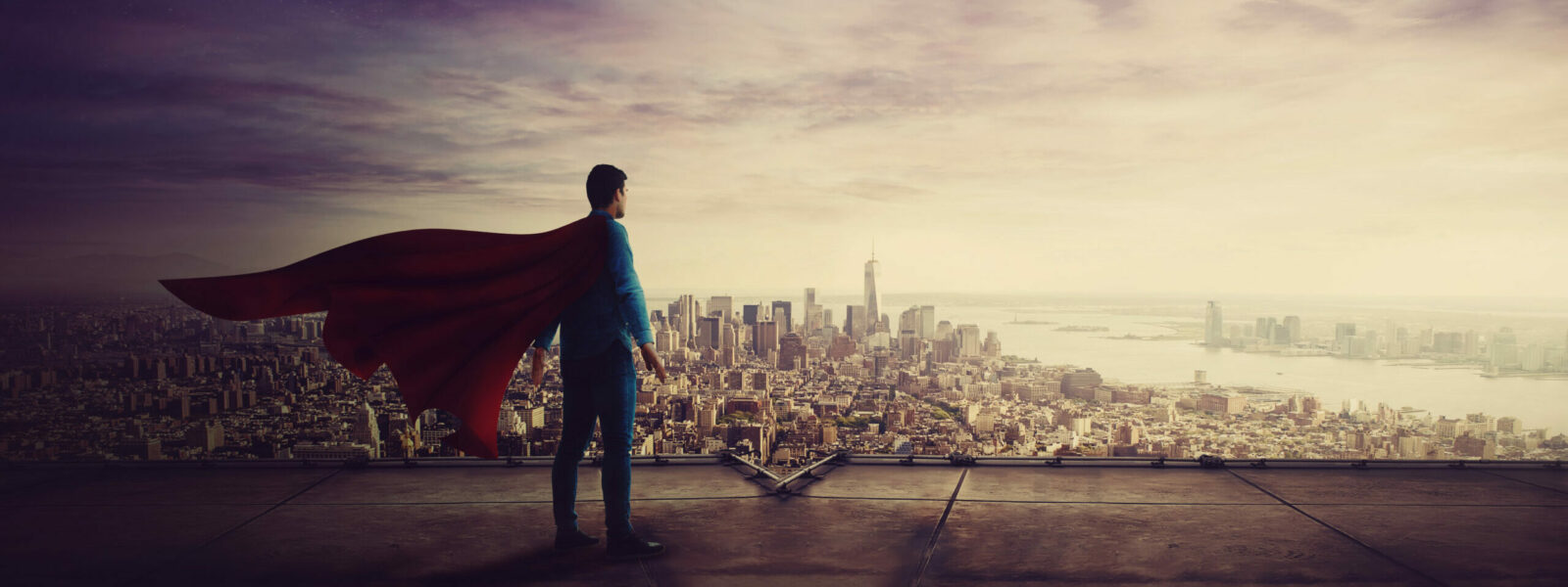 Rear view confident businessman, red cape suit, as hero stands o
