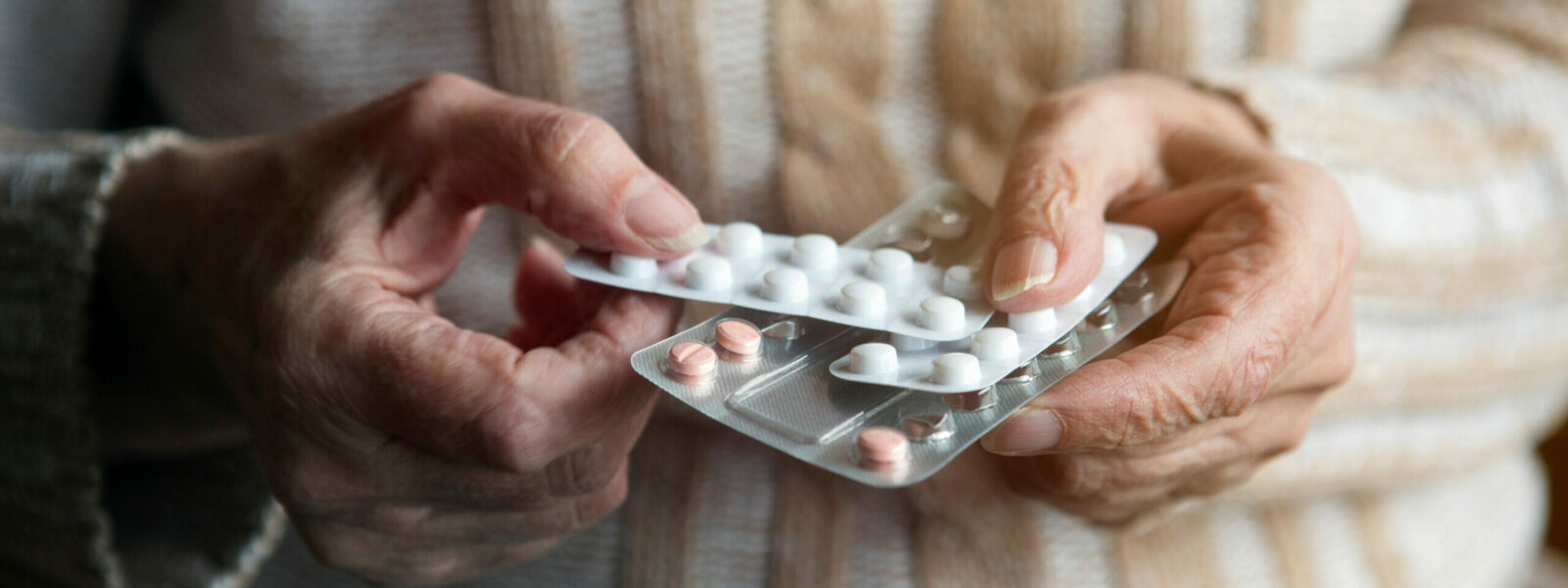 closeup of old female hands holding pills