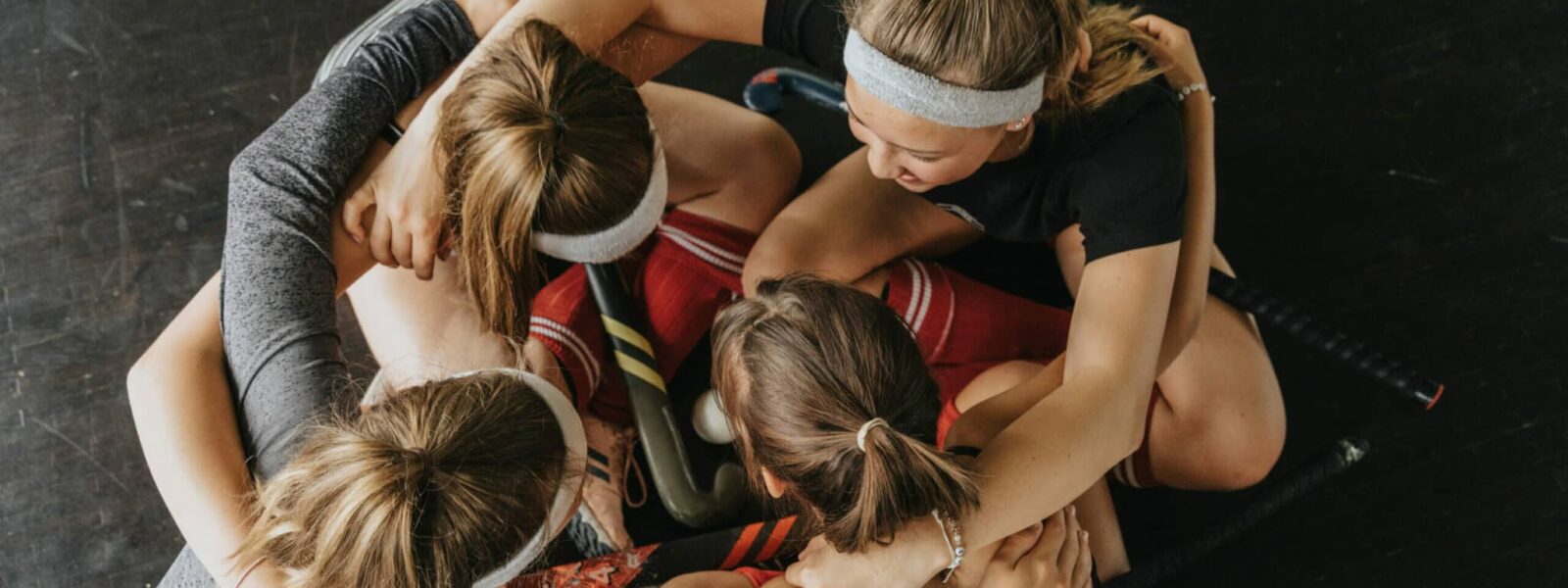 Hockey players huddling while crouching on floor in health club