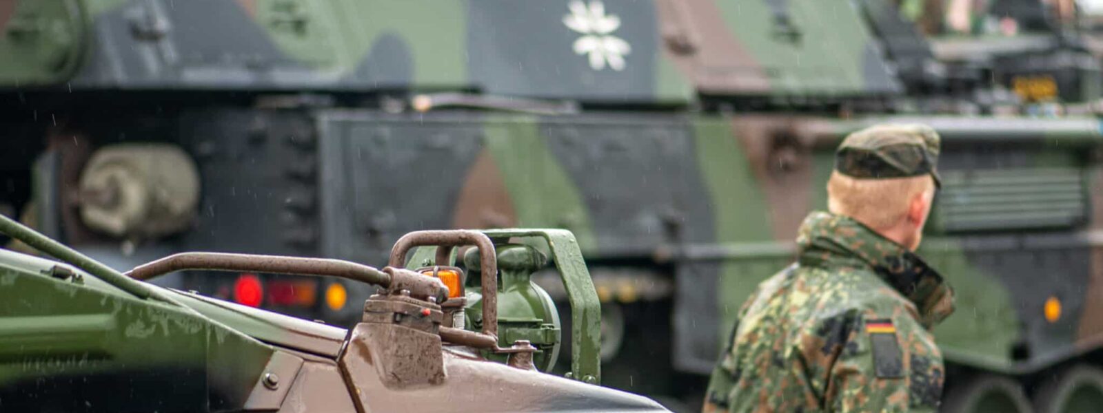 German soldier walking near moving armoured tanks self-propelled howitzer Panzerhaubitze 2000 or PzH 2000, German Army, Bundeswehr, NATO response force