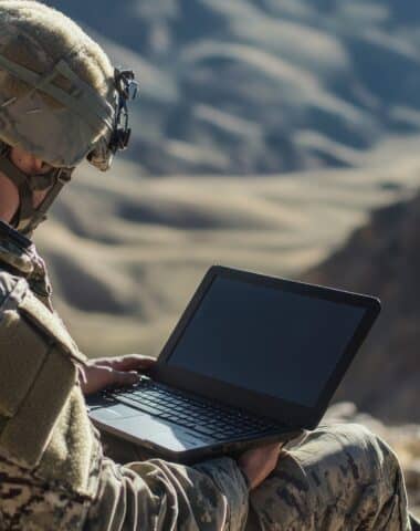 Soldier Using Laptop in Mountainous Terrain